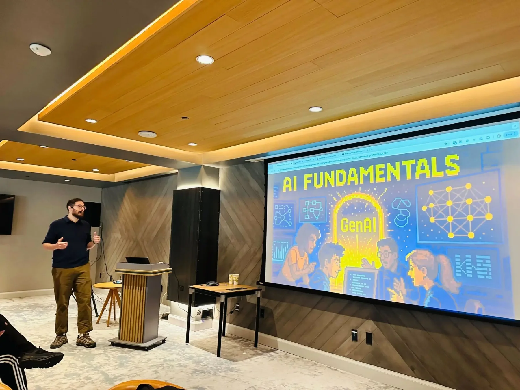 Zack teaching AI Fundamentals beside a large screen at WorkOS.