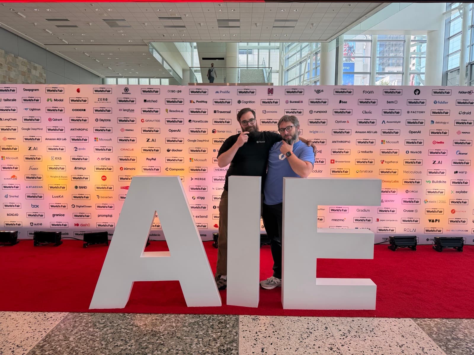 Zack Proser and Nick Nisi posing behind the giant AIE letters on the red carpet at Moscone West